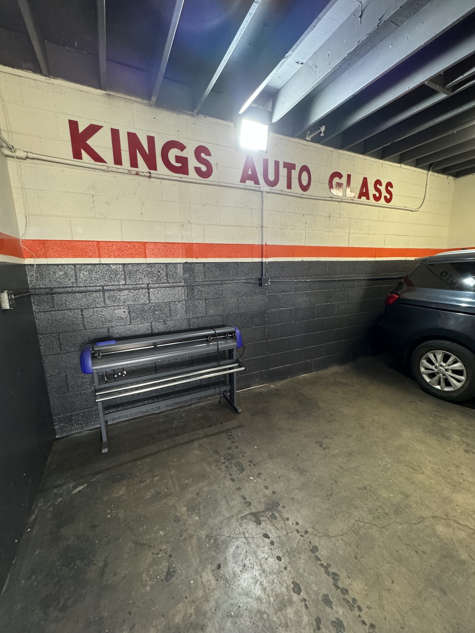 Interior garage bay with Kings Auto Glass painted wall and window tint film cutting machine